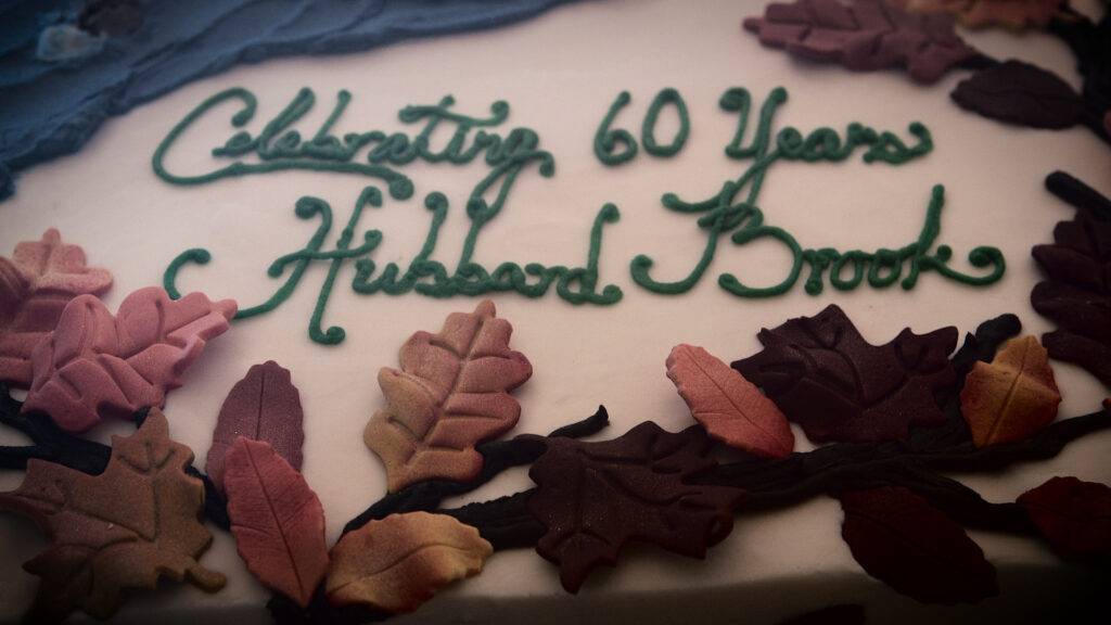 A cake decorated with autumn leaves and green icing that reads "Celebrating 60 Years Hubbard Brook.