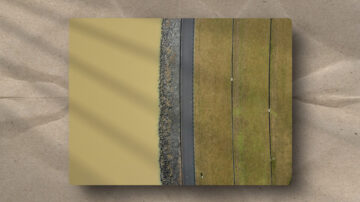 Aerial view of a dam illustrating a structural boundary. A rocky breakwater and road act as an interface between fluid water and terraced land.
