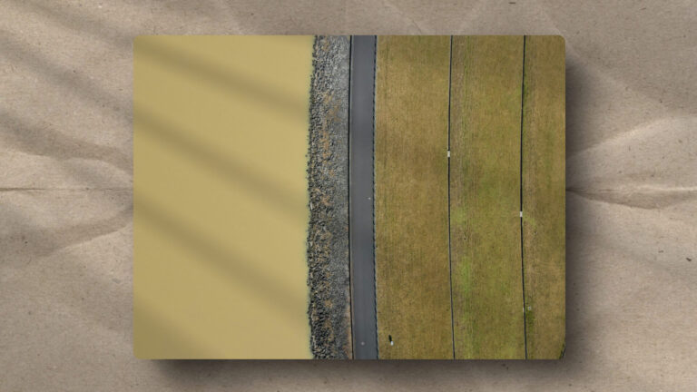 Aerial view of a dam illustrating a structural boundary. A rocky breakwater and road act as an interface between fluid water and terraced land.