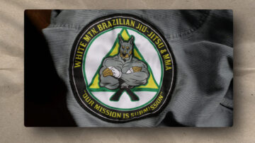 A fabric patch featuring a muscular, anthropomorphic dog in a gi with crossed arms, inside a green triangle. Yellow text reads “WHITE MTN. BRAZILIAN JIU-JITSU & MMA” and “OUR MISSION IS SUBMISSION” on a black background.